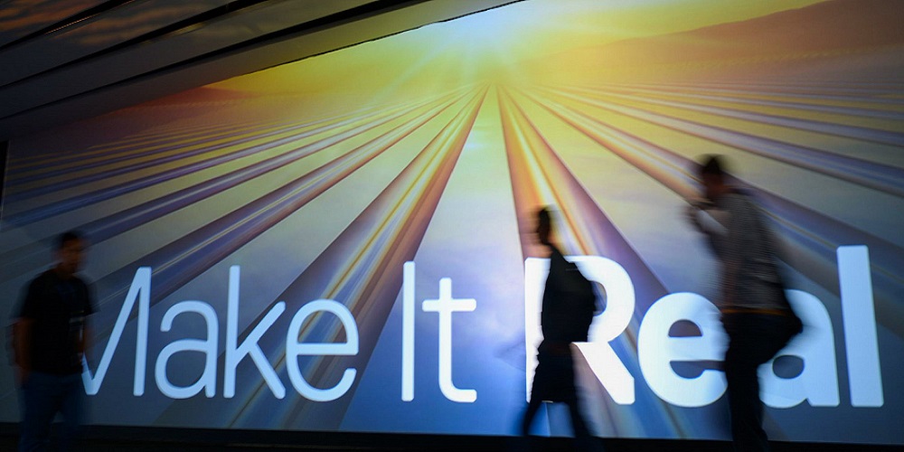 photo of three people walking in front of a sign that says make it real
